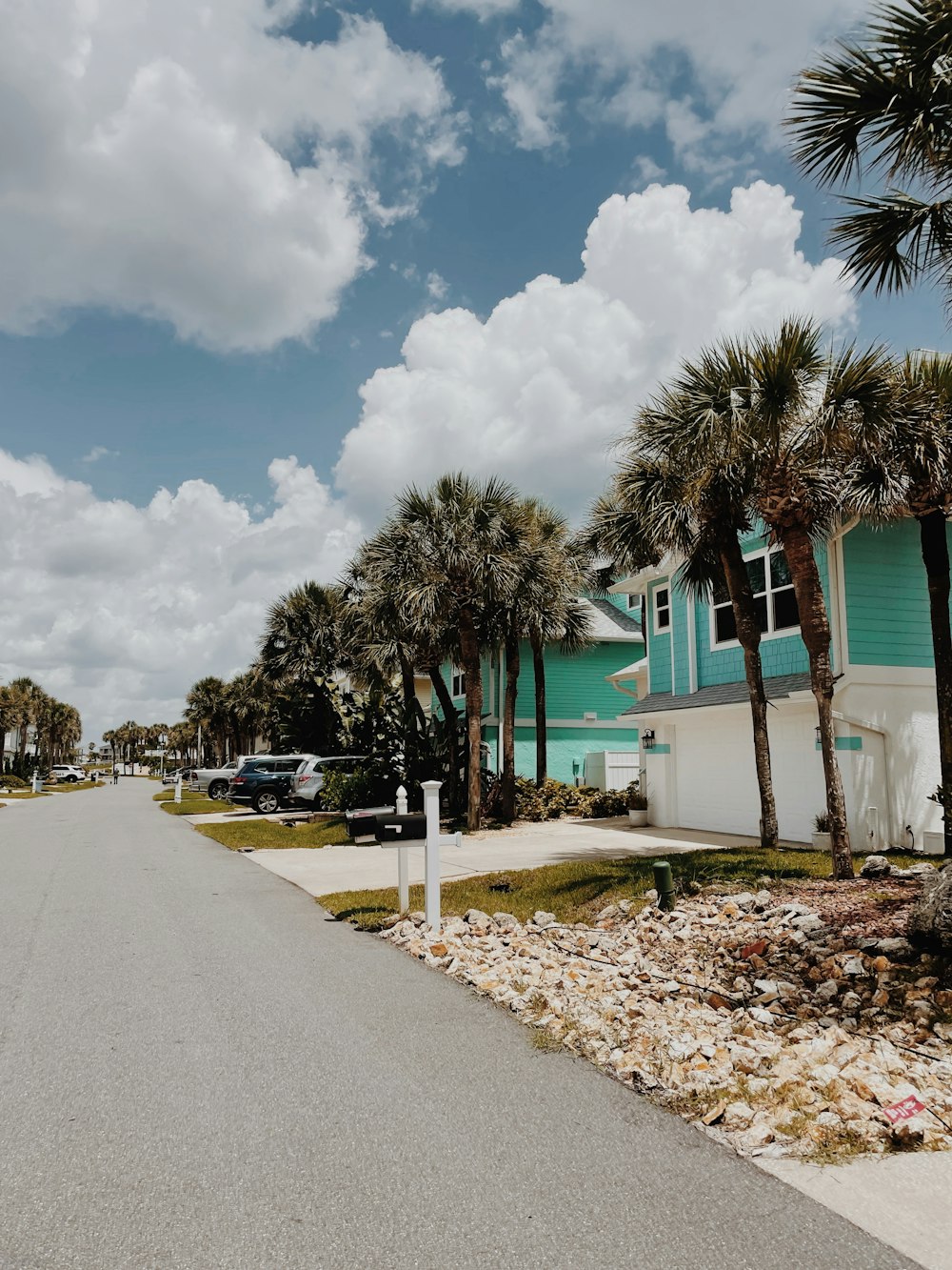 a street with palm trees and a building with a blue sky