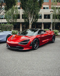 A shiny red sedan parked in a sunlit urban street, showcasing its sleek design.