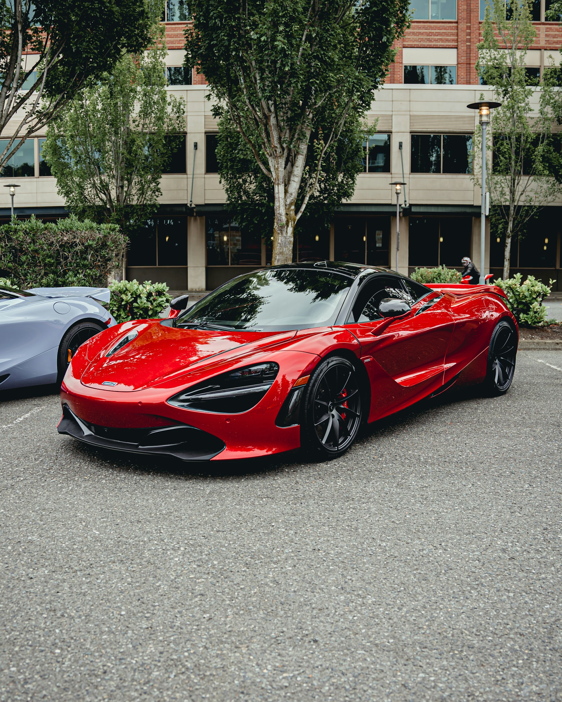 A sleek black car partially wrapped in a glossy, vibrant red hentair wrapping film, parked in a modern Shenzhen cityscape.