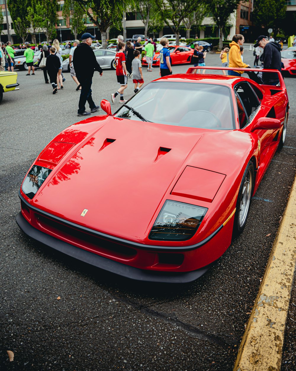 a red sports car parked on the side of a road with people walking around