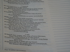 A close-up view of a printed page containing text in poetic format. The text appears to be organized in verses or stanzas, containing religious or spiritual content. The font is clear, and the page has margins with dotted lines on the side, possibly indicating space for notes.