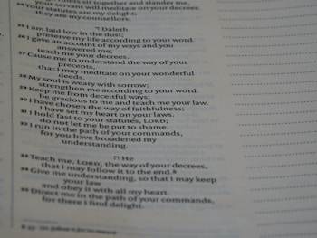 A close-up view of a printed page containing text in poetic format. The text appears to be organized in verses or stanzas, containing religious or spiritual content. The font is clear, and the page has margins with dotted lines on the side, possibly indicating space for notes.