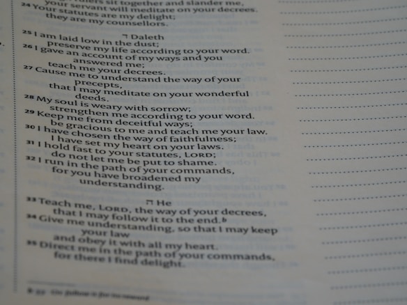 A close-up view of a printed page containing text in poetic format. The text appears to be organized in verses or stanzas, containing religious or spiritual content. The font is clear, and the page has margins with dotted lines on the side, possibly indicating space for notes.