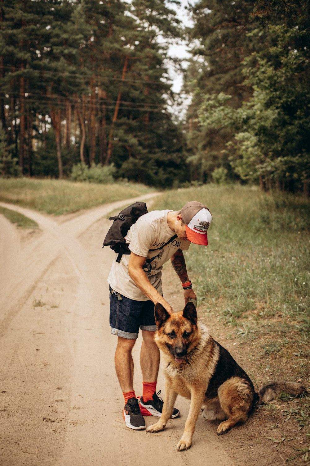 a man petting a dog on a dirt road