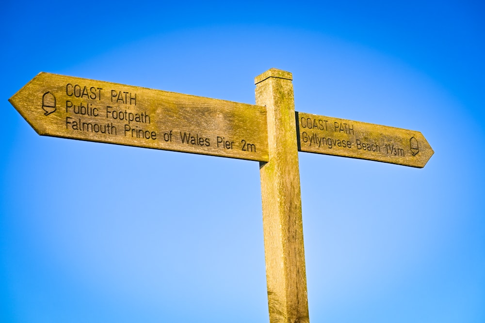 a wooden signpost with a blue sky in the background