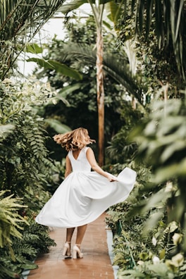 A joyful woman twirling in a flowing, elegant thrifted gown.
