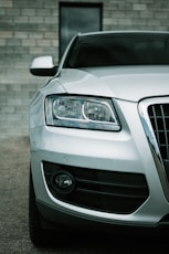a white car parked in front of a brick wall