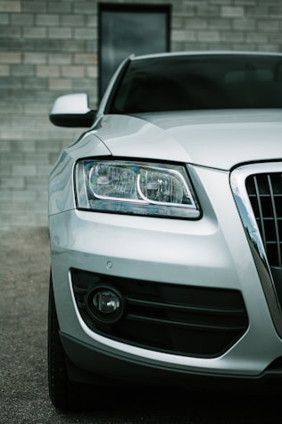 a white car parked in front of a brick wall