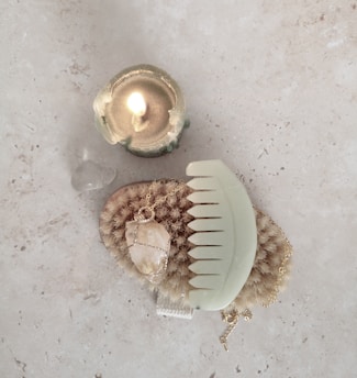 Hands arranging gemstones and candles on a wooden table framed with fresh flowers.