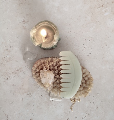 A peaceful scene showing a crystal bracelet beside a lit candle and smooth stones on a wooden table.