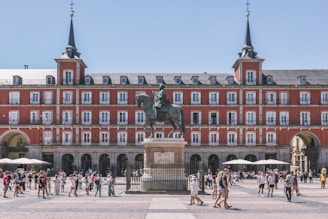 a large building with a statue in front of it with Plaza Mayor, Madrid in the background