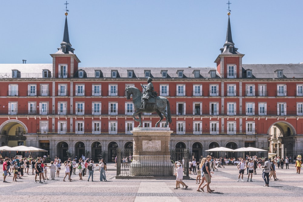 a large building with a statue in front of it with Plaza Mayor, Madrid in the background