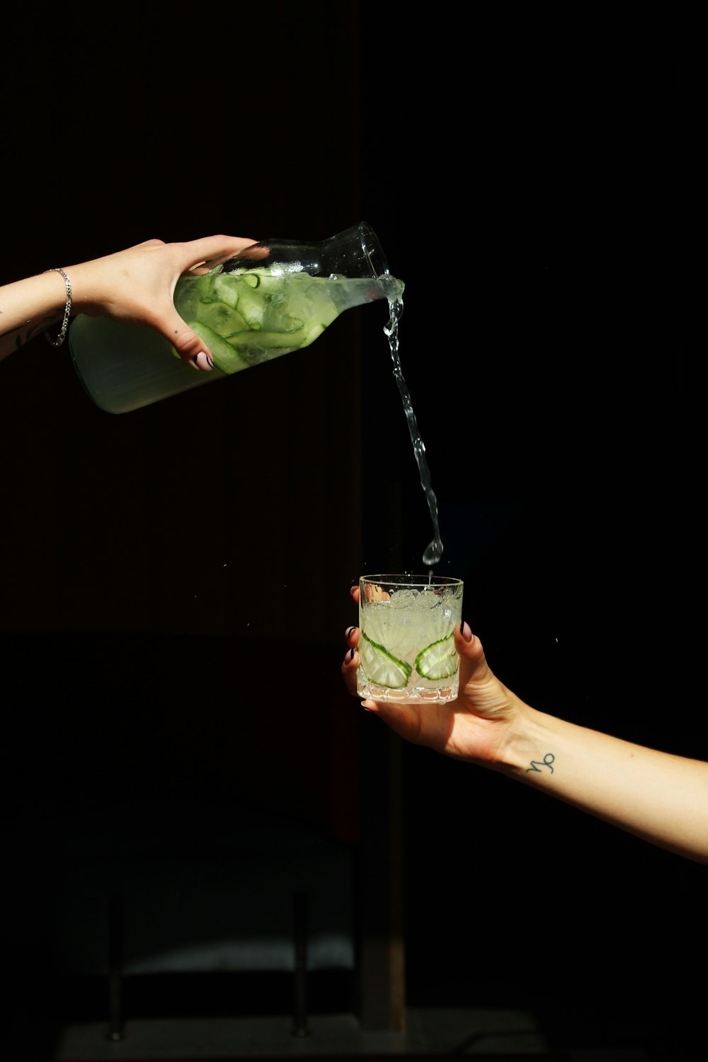 a person pouring a drink into a glass