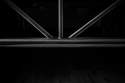 Metal rods form a geometric pattern, likely part of a structure or furniture piece, set against a dark background.