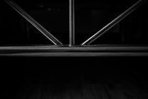 Metal rods form a geometric pattern, likely part of a structure or furniture piece, set against a dark background.