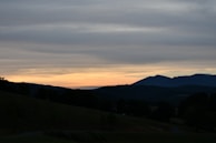 A serene landscape at dusk with gentle shadows blending into a foggy background