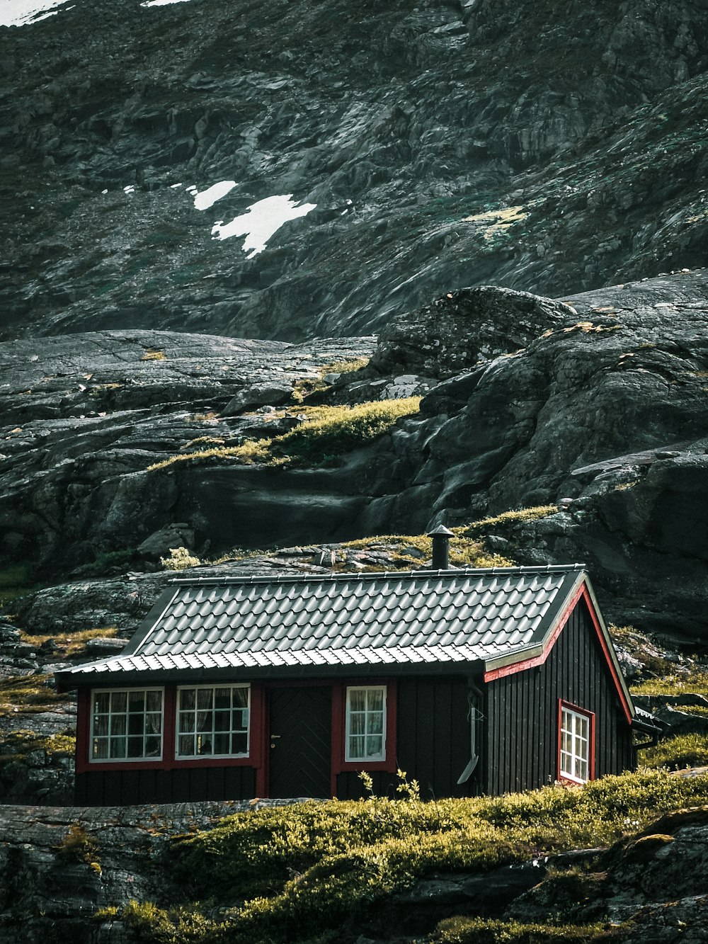 a red house in front of a rocky mountain
