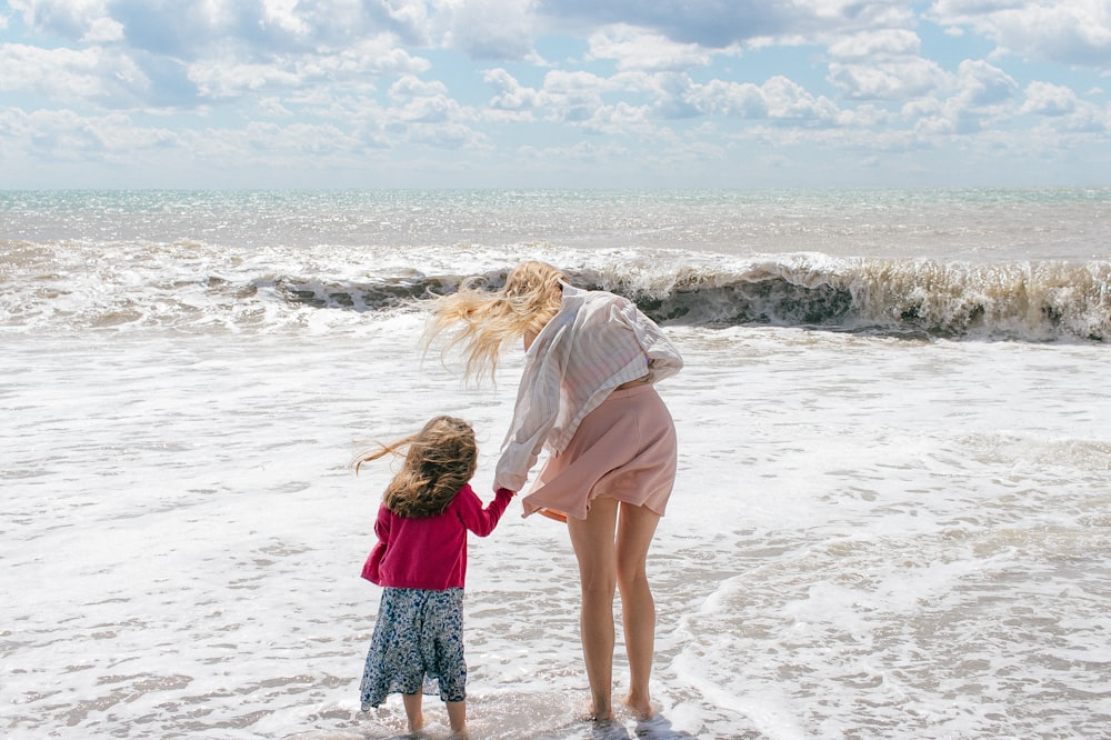 Una persona y un niño parados en una playa