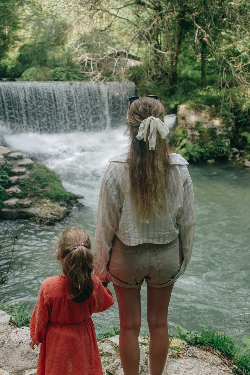 a person and a child looking at a waterfall