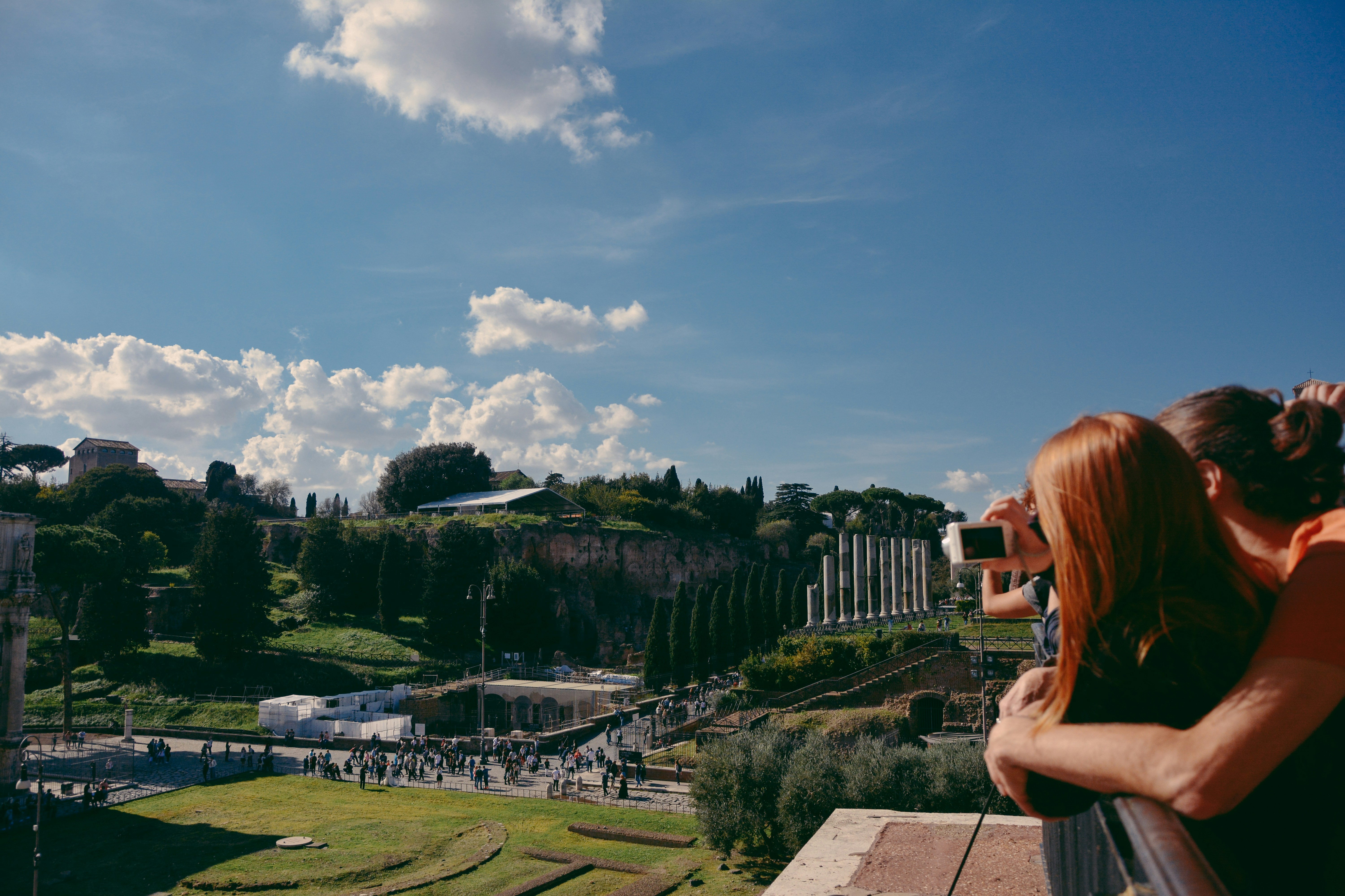 a person taking a picture of a park with a large group of people