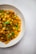 A close-up of a bowl filled with cooked chickpeas garnished with fresh cilantro. The chickpeas appear to be seasoned, displaying a rich, orange-brown color. The dish is presented on a neutral-colored surface, contributing to a comforting presentation.