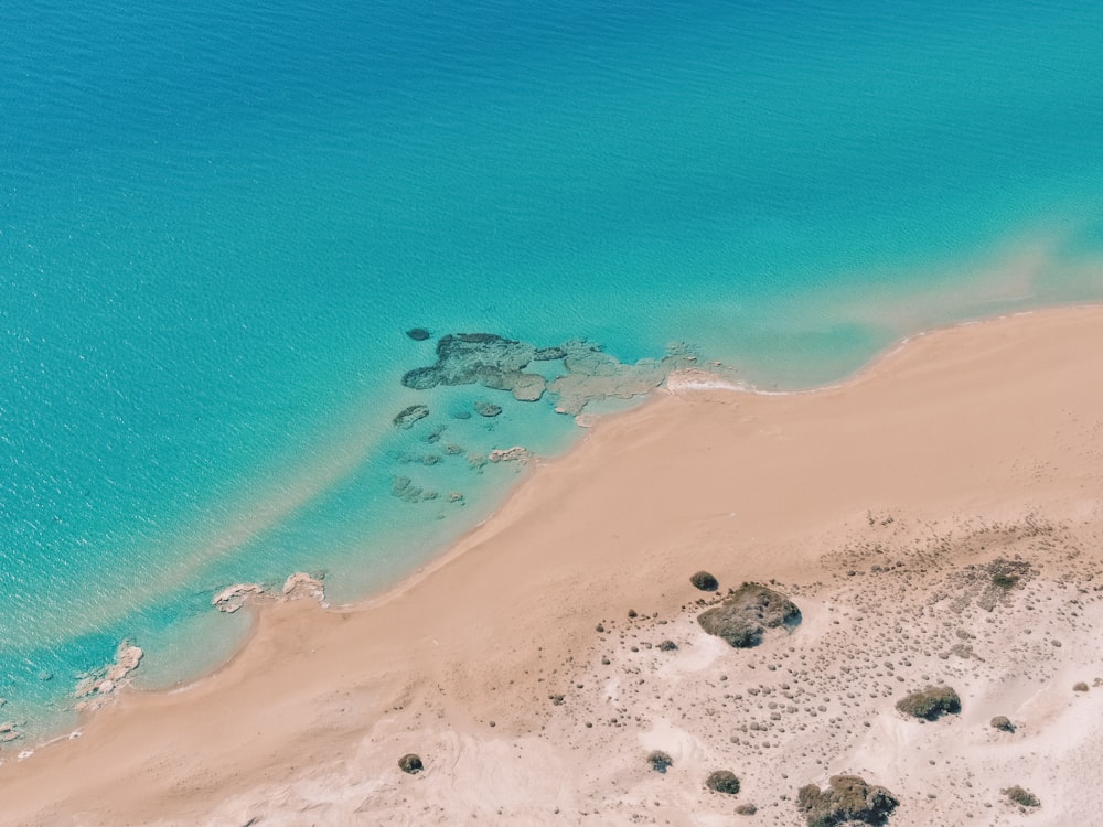 a sandy beach with rocks and water