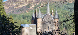 The gothic towers of Křivoklát Castle surrounded by lush green forest.