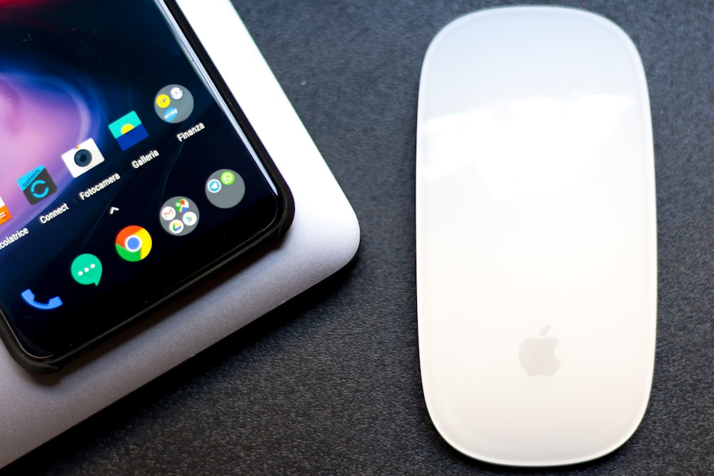 a white cell phone next to a white mouse