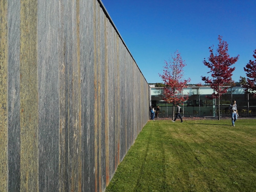 a group of people walking on a path between wooden fence posts