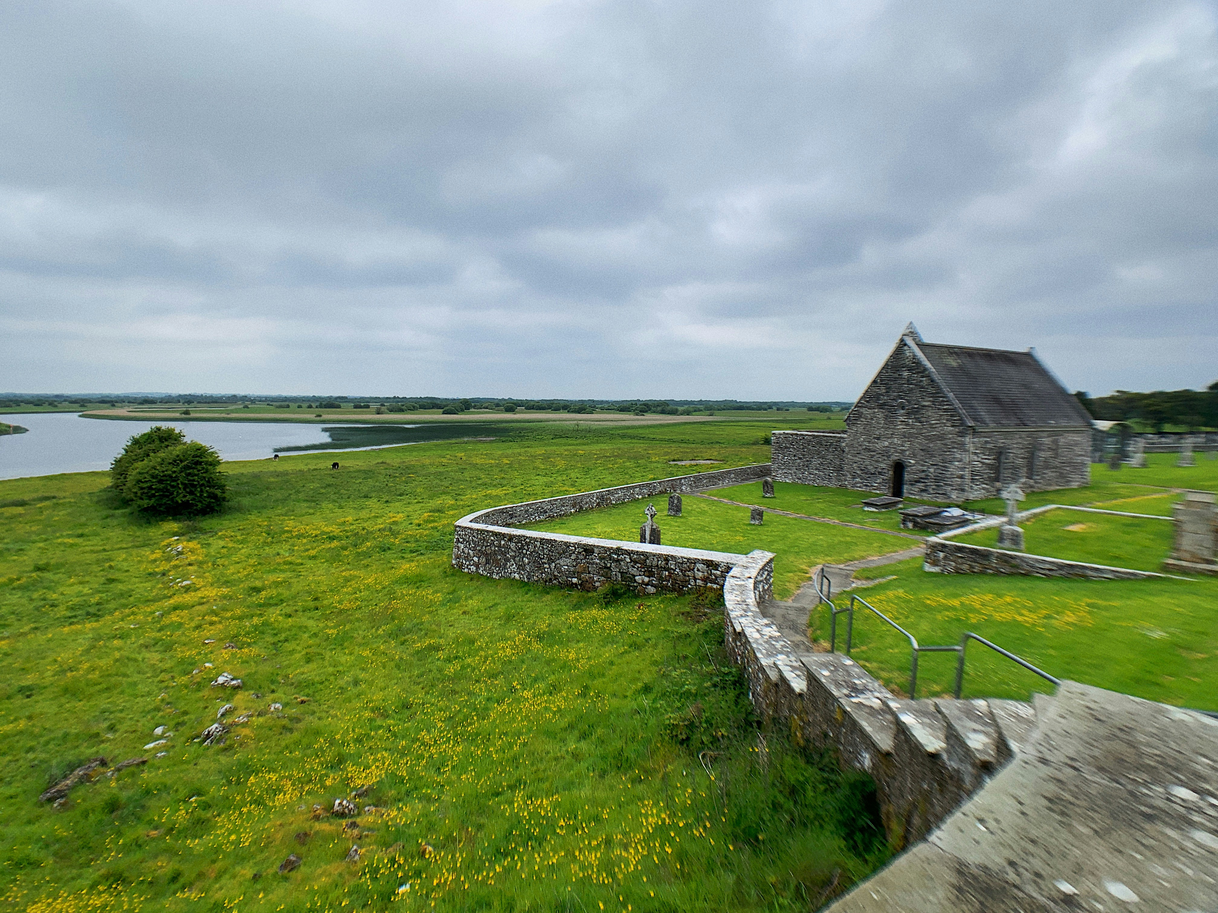 a stone building with a grass field and a body of water in the background