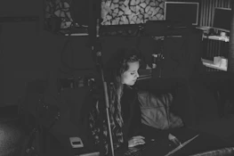 A candid shot of Beth working on her laptop in a cozy, monochrome workspace with yellow decor accents.