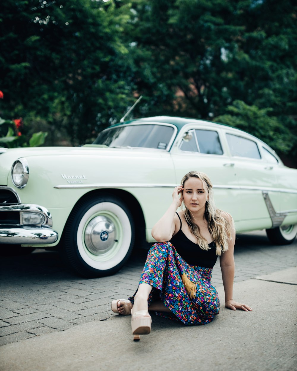 a person kneeling in front of a white car