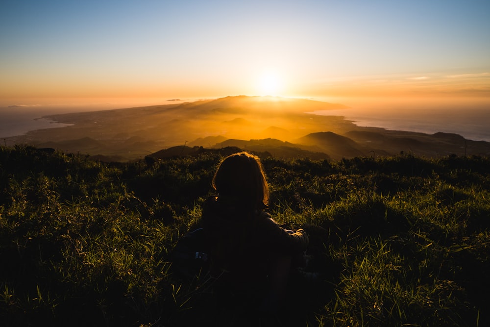 a person standing in a field with the sun setting in the background