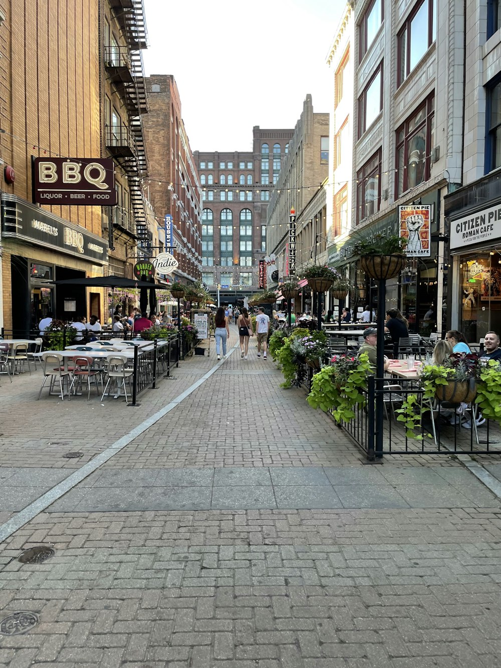 a brick road with tables and chairs on it and buildings on the side