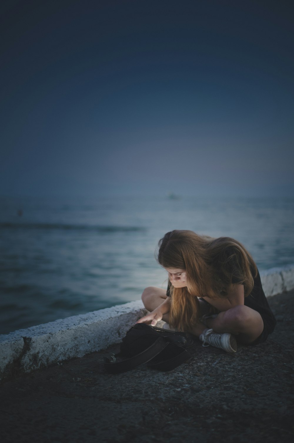 a person lying on a rock by the water