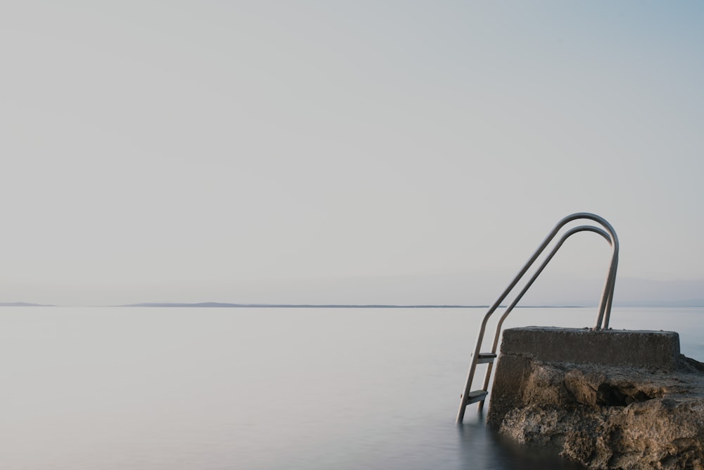 a metal bar on a rock in the water