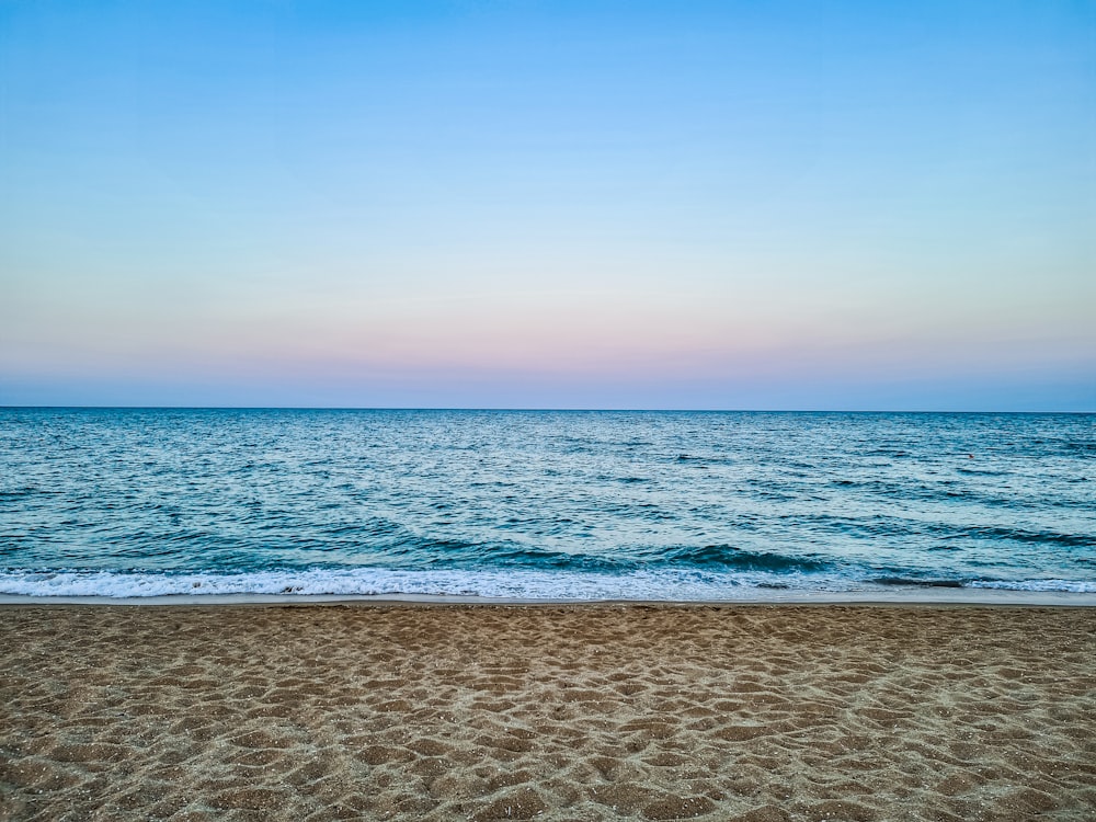 a beach with waves and a blue sky