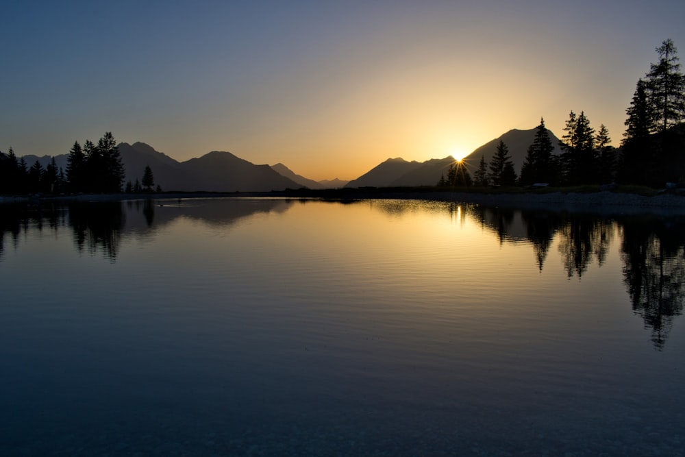 a lake with trees and mountains in the background