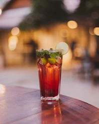 a glass of red liquid with a green leaf on top