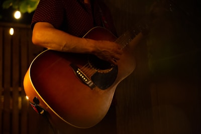 Close-up of hands playing an acoustic guitar in a cozy studio setting.