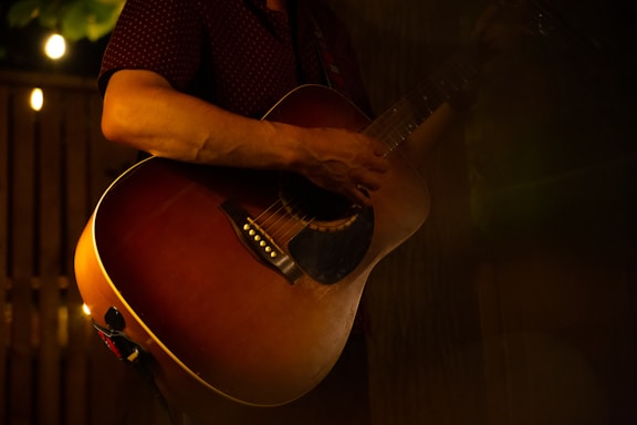 Close-up of hands playing an acoustic guitar in a warm indoor setting
