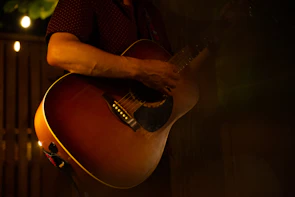 Hands playing an acoustic guitar in a cozy home studio.