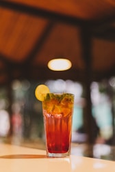 Elegant glass of mango lassi with a delicate mint garnish, set against a dark maroon backdrop.