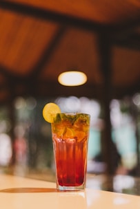 Elegant glass of mango lassi with a delicate mint garnish, set against a dark maroon backdrop.