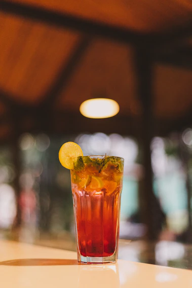 A vibrant mocktail glass garnished with fresh citrus and mint leaves on a clean cream background.