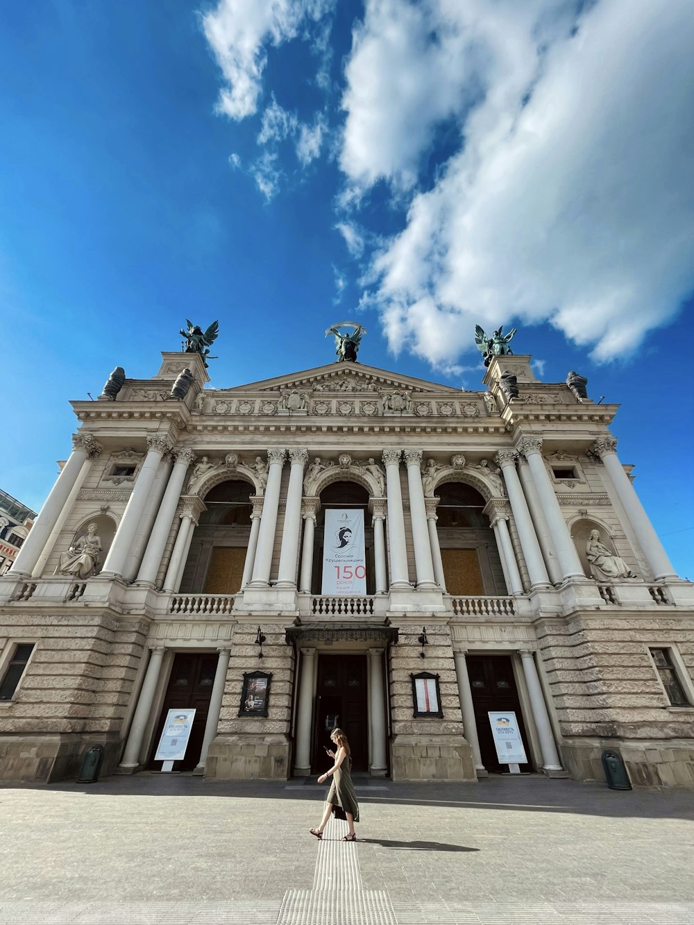 a person standing in front of a building with columns and statues