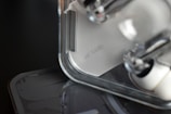 Close-up of a transparent and minimalistic electronic device with a textured surface. The focus is on the design details, showcasing clear plastic components and sleek lines.