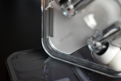 Close-up of a transparent and minimalistic electronic device with a textured surface. The focus is on the design details, showcasing clear plastic components and sleek lines.