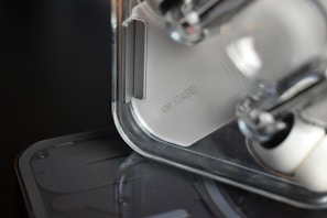 Close-up of a transparent and minimalistic electronic device with a textured surface. The focus is on the design details, showcasing clear plastic components and sleek lines.