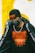 A person is wearing a black beanie hat with a Givenchy Paris logo, a black face mask, a black t-shirt with an orange tiger print and the words Kenzo Paris, a silver chain necklace, and a black jacket with white text along the sleeves.
